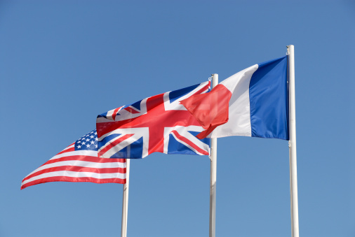 National flags of UK, USA and France against blue sky