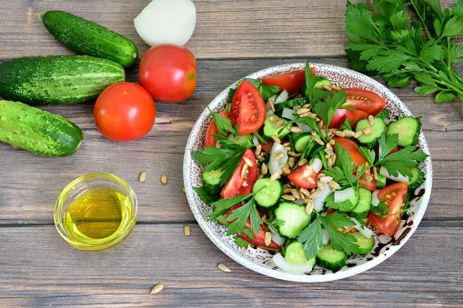 healthy vegetable salad with tomato, cucumber, parsley, seeds and olive oil, close-up