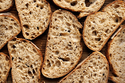 Close up of sliced buckwheat bread on a cutting board and cereals on the table top view