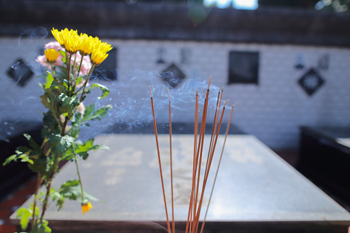 Bouquets of flowers and burning incense in front of the grave