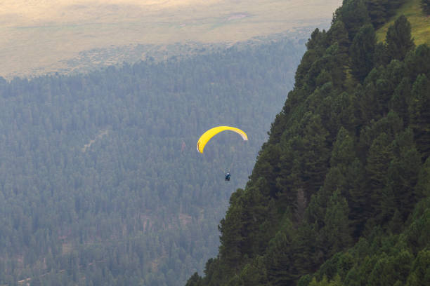 istock yellow paragliding fly near the mountains forest 1467582280
