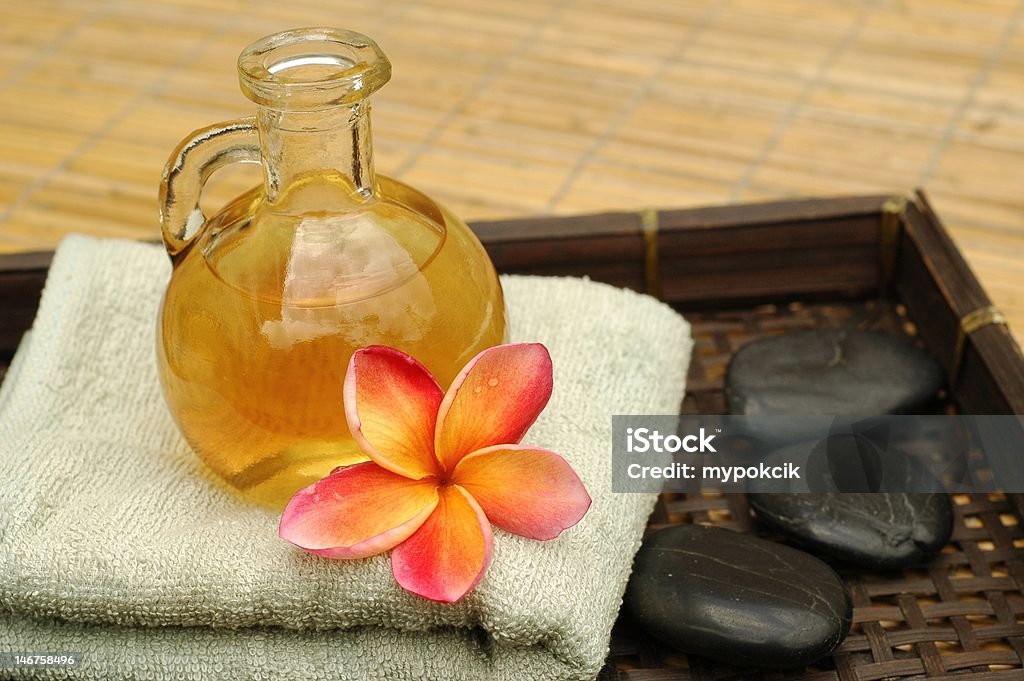 Tropical Spa Aromatic massage oil and tropical plumeria flower on towel Alternative Medicine Stock Photo