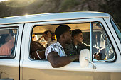 Young friends having fun on a road trip in retro mini van