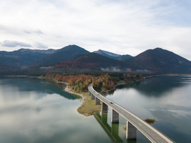 istock Car on a bridge, roadtrip and e-mobility. This stunning image captures the beauty of Sylvensteinsee, a picturesque lake located in Bavaria, Germany during autumn. 1467587179