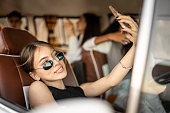 Young woman taking selfie or filming sitting on the passenger seat on retro mini van transport