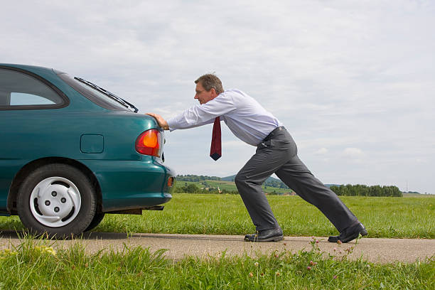 businessman pushing a car - vehicle breakdown stockfoto's en -beelden