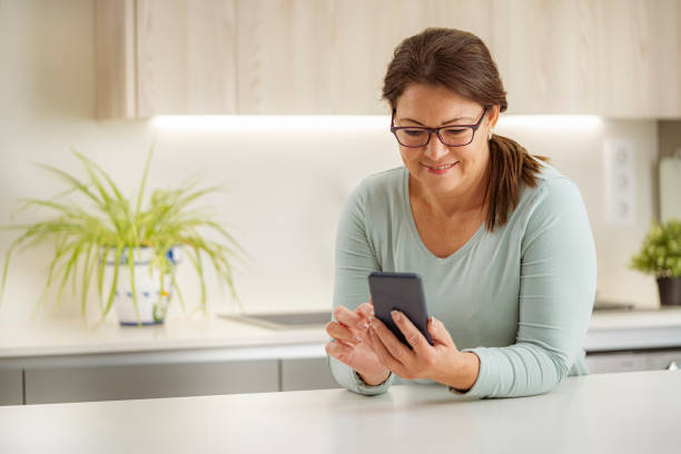 Smiling woman using smart phone at home stock photo