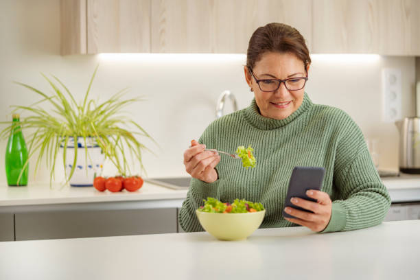istock Woman eating salad while using smart phone 1467593988