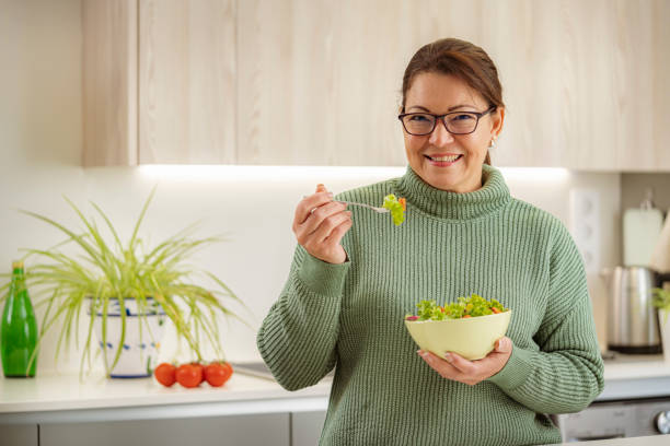 istock Happy woman eating fresh salad in kitchen 1467594851