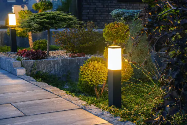 Closeup of Glowing Bollard Lamp in Residential Backyard Garden. Outdoor Lighting and Illumination Theme.