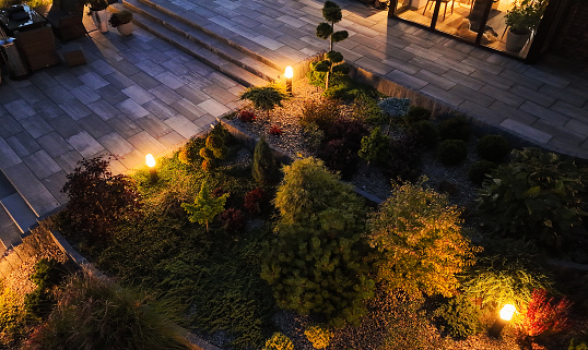 Professionally Maintained and Beautifully Arranged Backyard Garden Illuminated with Outdoor Bollard Lamps. Aerial View, Evening Time.
