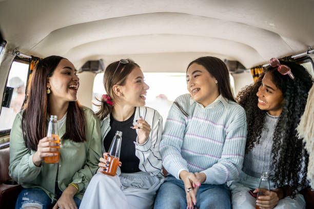 Girlfriends talking while drinking soda on retro mini van transport