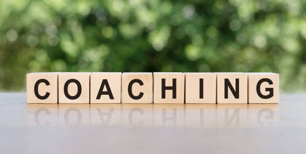 istock COACHING. Word written on wooden blocks. The text is written in black letters and is reflected in the mirror surface of the table. Business concept for your design. 1467605900