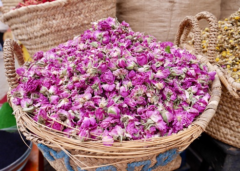Close up of heap of dried rose flowers in straw basket in the souk of Marrakech, Morocco.