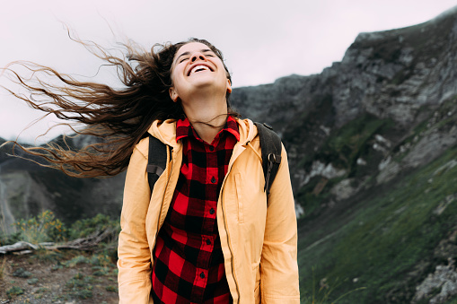 Young happy laughing carefree woman with hair blowing in the wind.