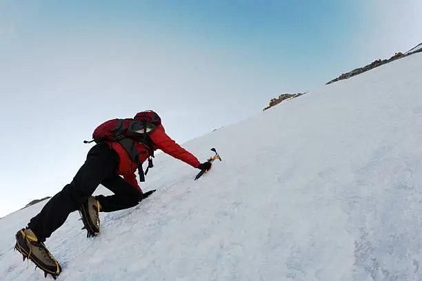 Mountaineer climbing a steep route on a icy slope, italian Alps, Europe.