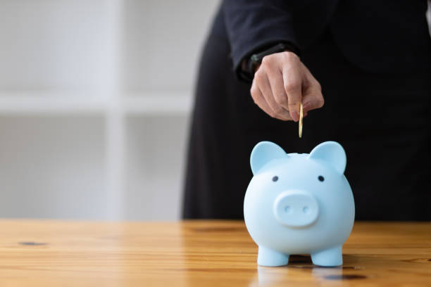 Business woman holding a piggy bank inserting coins. Concept of savings. Business woman holding a piggy bank inserting coins. Concept of savings. Salary Potential stock pictures, royalty-free photos & images