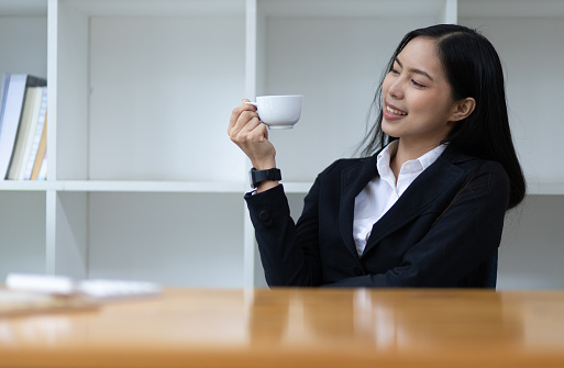 Portrait businesswoman, attractive young Asian woman in a good mood drinking coffee in the morning.