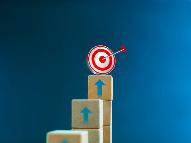 istock 3d target icon on the top of wooden cube blocks, bar graph chart steps with up arrows on blue background. Business growth process, investment, income, trends, inflation, economic improvement concepts. 1467617736