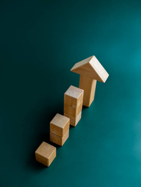 istock Big arrowhead wooden on cube blocks bar graph chart steps on dark blue background, top view, vertical style. Investment, income, trends, inflation, business growth, economic improvement concepts. 1467617774