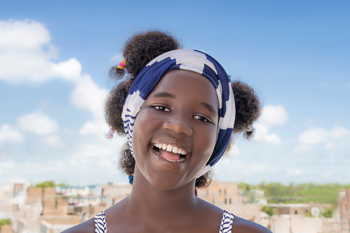Cheerful girl standing on a terrace, Afro hairstyle and pigtails, photo