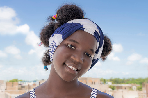 Smiling girl standing on a terrace, Afro hairstyle and pigtails, photo