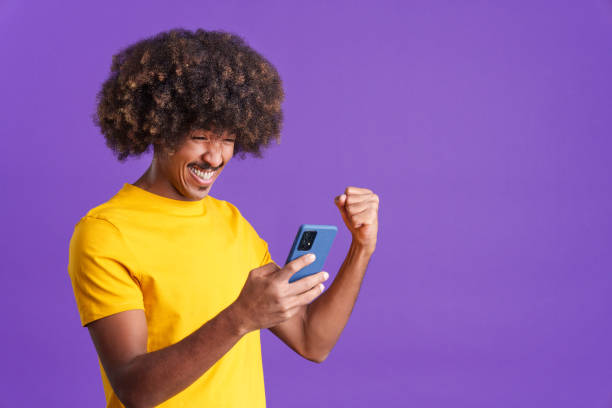 istock Excited african man celebrating while using the mobile phone 1467624115
