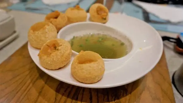 Pani Puri or Golgappa or Puchkas from a white plate which is popular Indian Chat menu.
