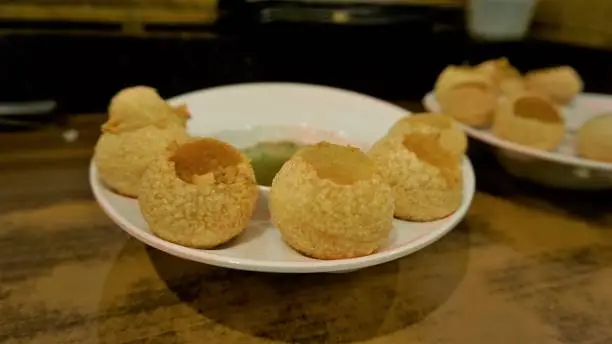 Pani Puri or Golgappa or Puchkas from a white plate which is popular Indian Chat menu.