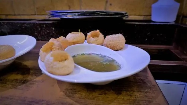 Pani Puri or Golgappa or Puchkas from a white plate which is popular Indian Chat menu.