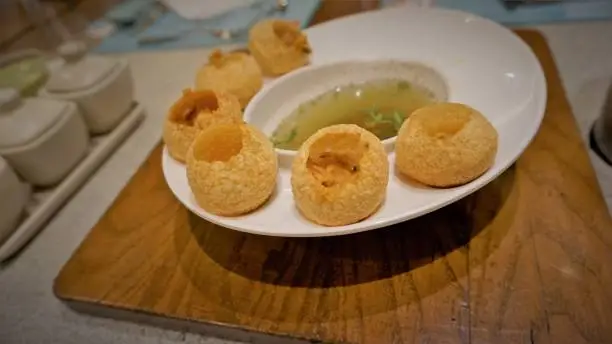 Pani Puri or Golgappa or Puchkas from a white plate which is popular Indian Chat menu.