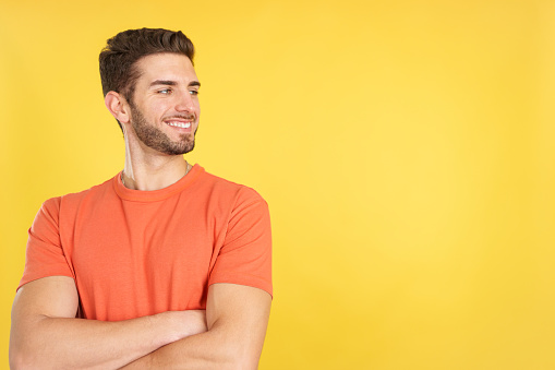 Caucasian man smiling while looking to the side in studio with yellow background