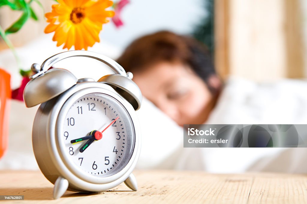 Woman dreaming through her wake up time Close up view of  table clock and woman sleeping on back Adult Stock Photo