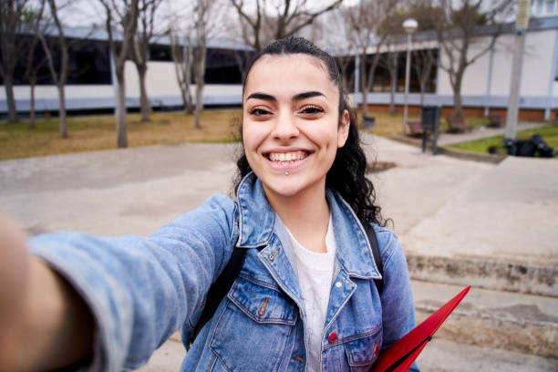 Selfie cheerful and happy Caucasian teenager looking smiling at camera in high school playground. stock photo