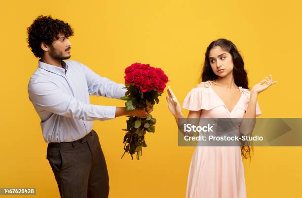 Unwanted Confession Displeased Indian Lady Rejecting Her Admirer With Roses On Valentines Day Yellow Background Stock Photo - Download Image Now