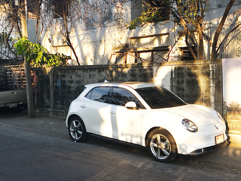White colored electric vehicle brand GWM Orio model is parked in street in residential district of Bangkok Chatuchak