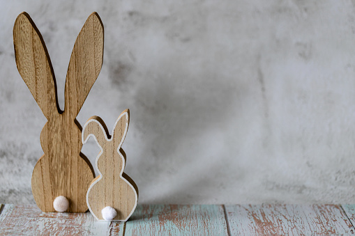 Two wooden Easter bunnies on a light concrete background, Easter greeting card, copy cpace.