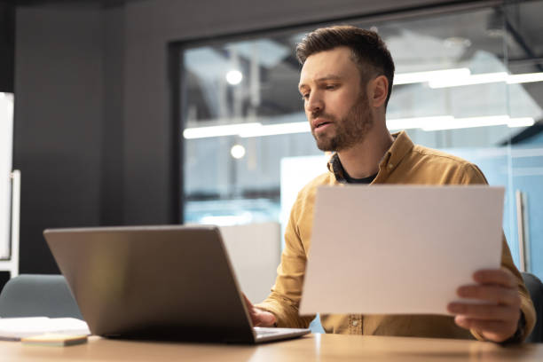 istock Businessman Using Laptop Holding Paper Working At Workplace In Office 1467632080