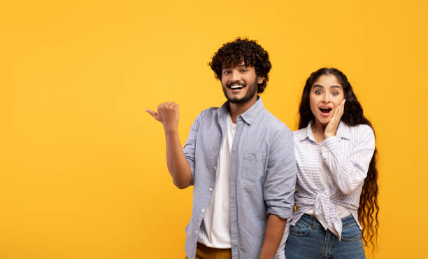 istock Omg, check this. Emotional indian guy pointing finger at free space, surprised lady looking at camera, panorama 1467632193