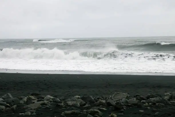 Striking Black Sand Beach in Iceland with Crashing Waves and Majestic Mountain Backdrop.