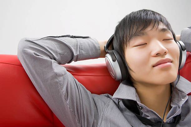 이 젊은 남자 헤드폰 예약하여 음악 듣기 스톡 사진