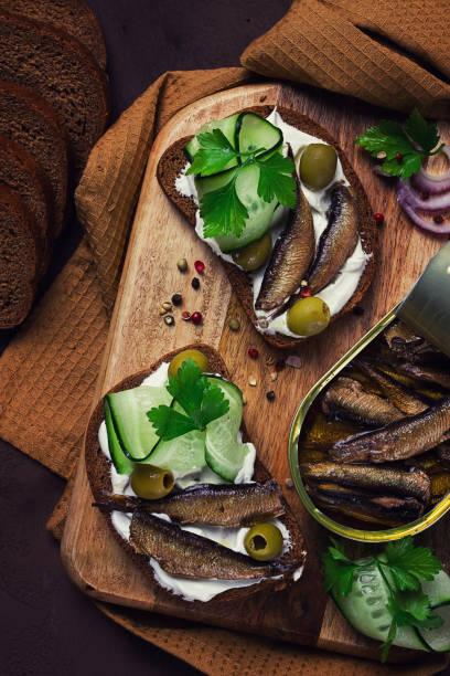 istock Sandwiches , black bread with sprats, cream cheese, cucumbers, on a cutting board, top view, close-up, no people, 1467641316