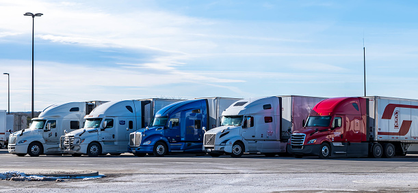 Sommerset, Pennsylvania, USA February 5, 2023 Five 18 wheeler freight trucks lined up at a rest stop on a sunny winter day
