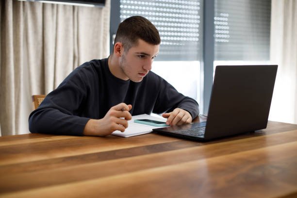 istock Teenage boy studying with laptop at home 1467649630