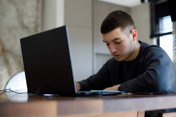 istock Teenage boy studying with laptop at home 1467649637