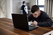 istock Teenage boy studying with laptop at home 1467649697