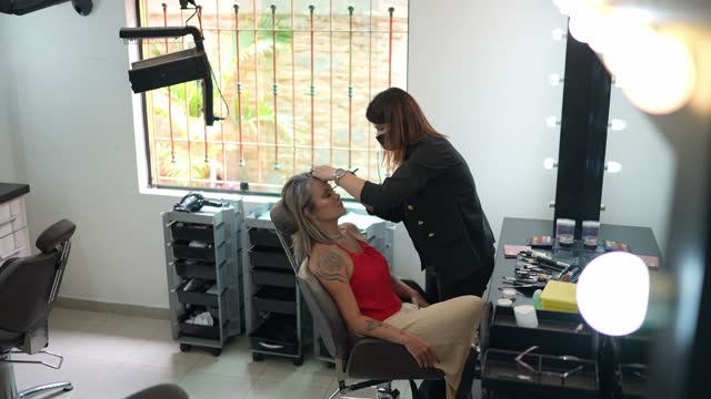 Beautician doing make-up for a woman at a beauty salon