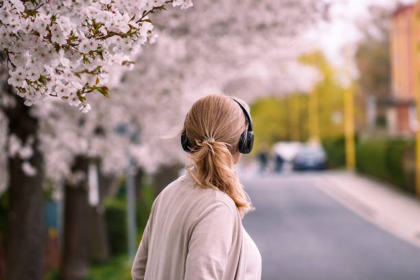 woman with wireless headphones walks on city street and listening music - back alley audio imagens e fotografias de stock