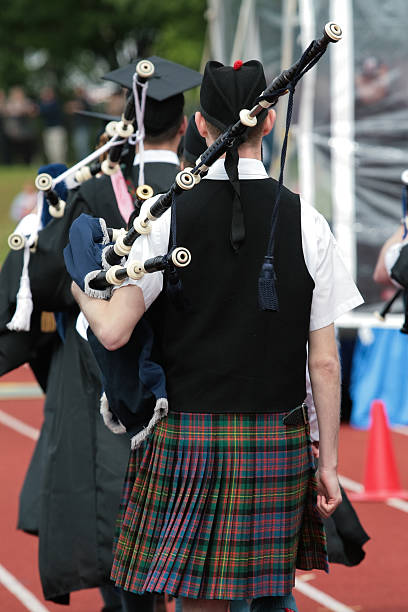 Bagpipe player walking down a track stock photo