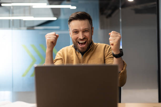 istock Emotional Business Man Shouting Shaking Fists Using Laptop At Workplace 1467665152